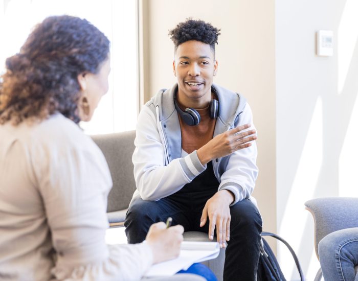 Mental health professional listens intently as a young man shares during therapy session.